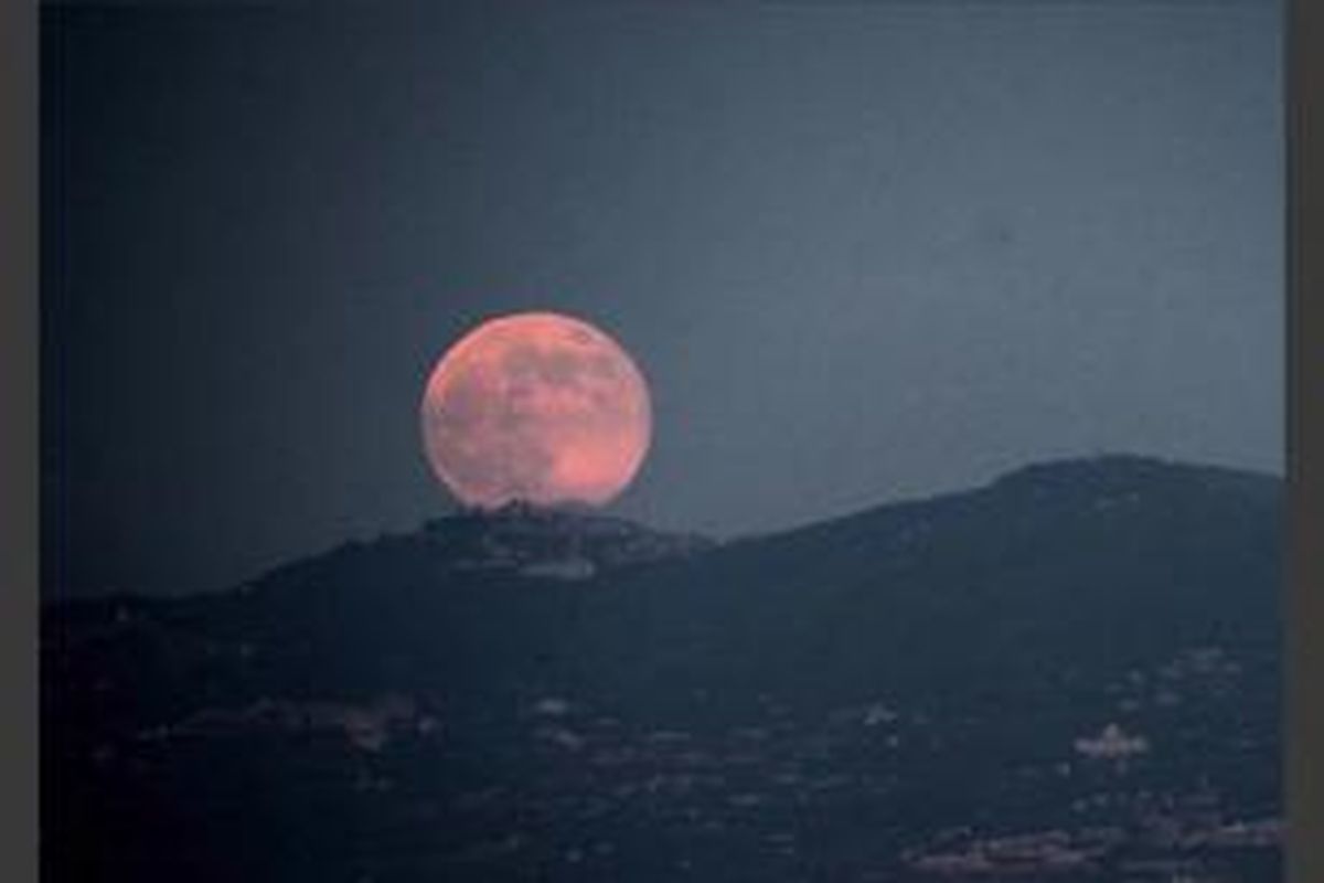 Bulan purnama terbit di atas kota Roma, 23 Juni 2013. Bulan yang akan mencapai tahap penuh pada Minggu, 14 persen lebih dekat ke bumi dan dikenal sebagai fenomena supermoon.