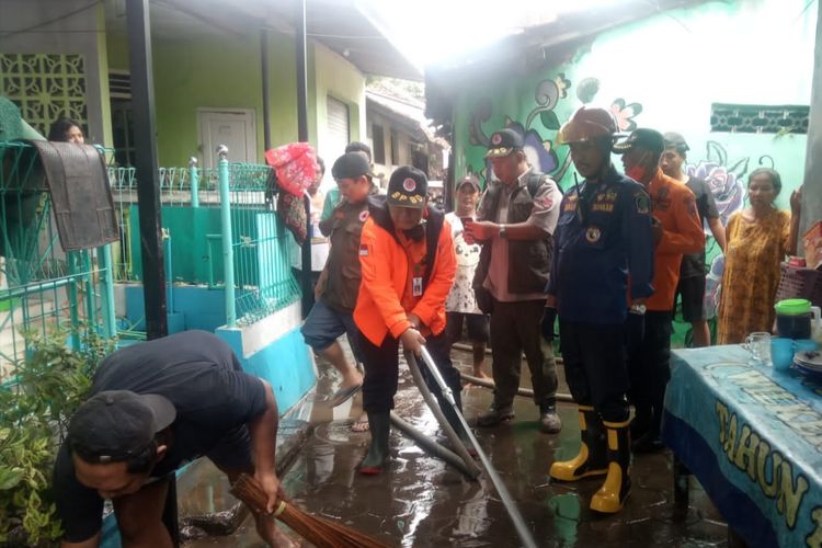 Petugas saat berusaha membersihkan sisa material banjir 