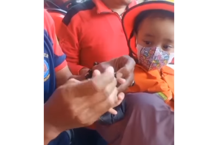 Tangkapan layar video yang memperlihatkan proses pelepasan tutup parfum yang menyangkut di jari telunjuk seorang anak oleh petugas pemadam kebakaran (damkar).