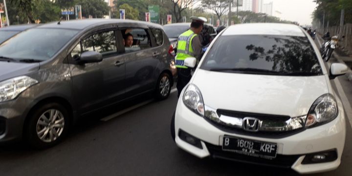 Polisi menghentikan mobil yang melanggar aturan ganjil-genap di Jalan Benyamin Sueb, Jakarta Utara, Rabu (1/8/2018).