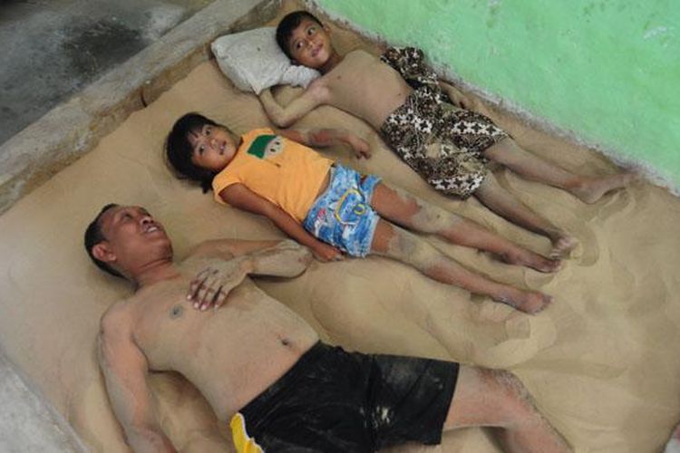 Junaidi bersama kedua anaknya, menikmati tidur berkasur pasirnya di rumahnya. Di desa Legung Timur, Legung Barat dan Dapenda, setiap rumah dipastikan ada tempat khusus untuk dijadikan tempat tidur berkasur pasir.