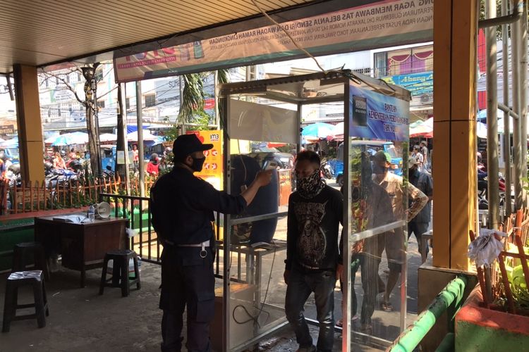 Petugas keamanan Pasar Kebayoran Lama, Jakarta mengukur suhu pengunjung sebelum memasuki area pasar, Senin (6/7/2020). Pengukuran suhu adalah salah satu protokol kesehatan yang diterapkan di pasar pada masa PSBB Transisi.