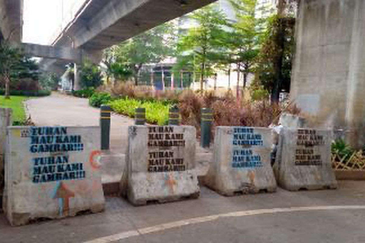 Coretan bentuk stensil bertuliskan “Tuhan Mau Kami Gambar” terlihat di sejumlah Moveable Concrete Barrier (MCB) di putaran arah Jalan Prof. Satrio tepatnya di seberang Lotte Shopping Avanue, Karet Kuningan, Setiabudi, Jakarta Selatan pada Senin (23/8/2021) sekitar pukul 07.30 WIB.