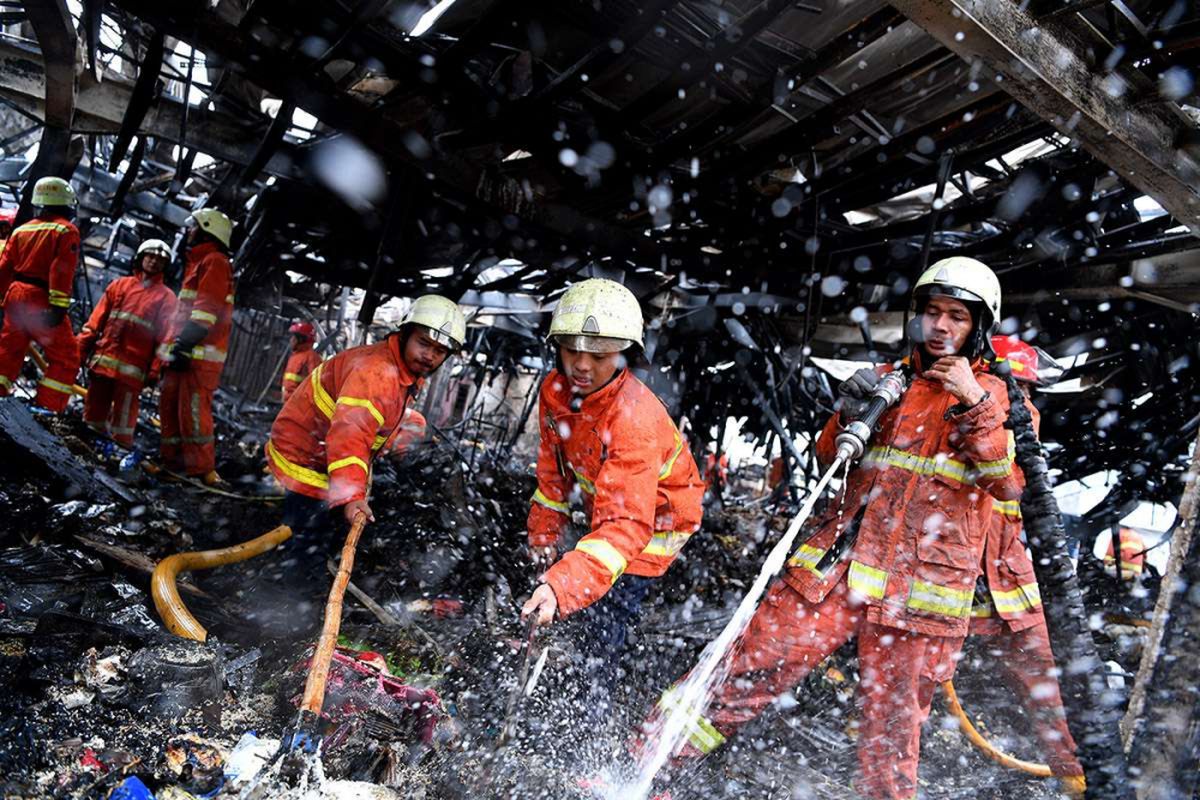 Petugas pemadam kebakaran mendinginkan sisa kebakaran di Tempat Penampungan Sementara Pasar Blok A, Kebayoran Baru, Jakarta Selatan, Rabu (6/3/2019). Kebakaran yang diduga karena korsleting listrik tersebut menghanguskan sekitar 414 kios.