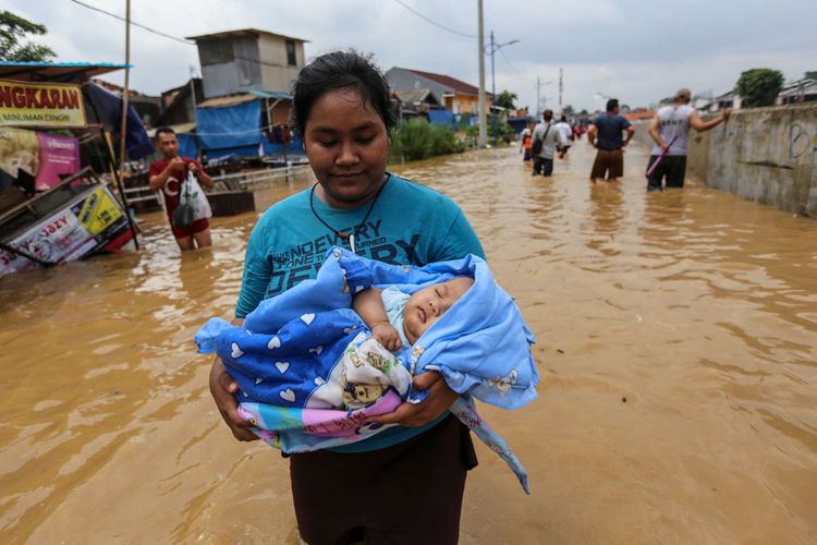 Warga berjalan melintasi banjir di Kampung Pulo, Jatinegara, Jakarta Timur, Selasa (6/2/2018). Banjir merendam ratusan rumah warga akibat luapan air dari Sungai Ciliwung.