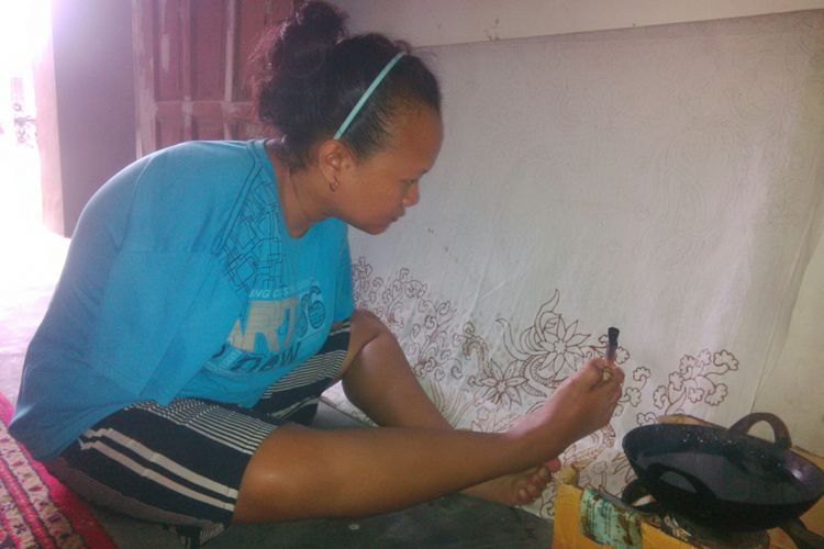 Ayu Tri Handayani (27), pembatik difabel menggunakan kaki kanannya saat membatik di ruang tamu rumahnya Desa Sawahan, Ngemplak, Boyolali, Jawa Tengah, Senin (13/8/2018).
