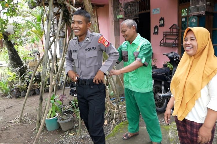 Sumartana dan istri Retno Indah Utami membantu anaknya Larang Bimo Tri Sembodo mengenakan seragam polisi