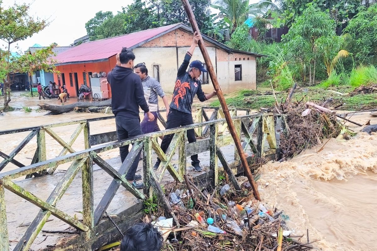 Petugas BPBD Nunukan mencoba menyingkirkan sampah yang menghambat aliran sungai. Banjir bandang melanda Nunukan Senin (3/8/2026), BPBD mencatat 345 rumah warga terendam dan 60 hektar sawah baru tanam rusak akibat terjangan banjir.