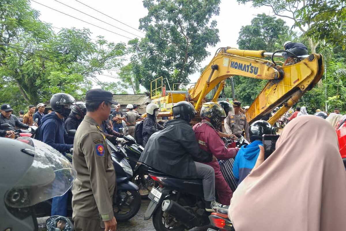 Sebuah alat berat jenis beko yang diangkut truk trailer terlepas dan jatuh di Tanjakan Mengker, Desa Sirnagalih, Kecamatan Jonggol, Kabupaten Bogor, Sabtu (3/1/2026). Kecelakaan lalu lintas ini menyebabkan sejumlah mobil dan motor rusak parah karena tertimpa beko.