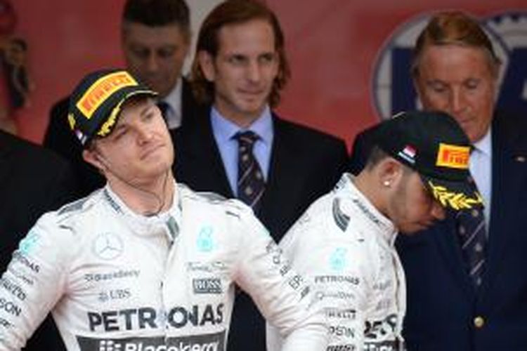 Pebalap Mercedes asal Jerman, Nico Rosberg (kiri), yang finis pertama pada GP Monaco, berdiri di samping rekan satu timnya yang finis kedua, Lewis Hamilton, di podium Sirkuit Monte Carlo, Minggu (24/5/2015).