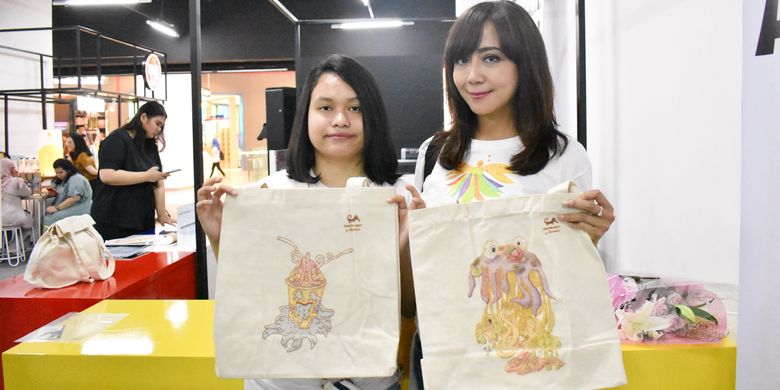 Sophia (kanan) dan anaknya, Anindhita (kiri) yang memiliki gangguan autisme menunjukkan gambar karya Anindhita di tote bag.