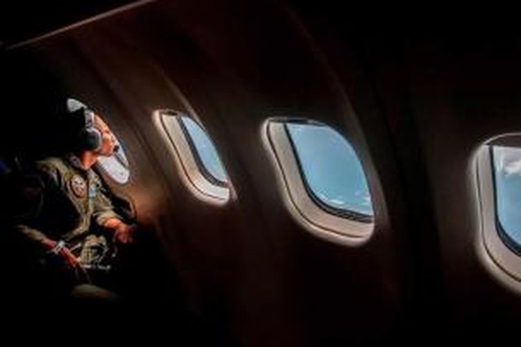 Anggota TNI melakukan pengamatan dari jendela pesawat dalam operasi pencarian pesawat AirAsia QZ8501, di atas Laut Jawa, Senin (29/12/2014). Pesawat AirAsia QZ8501 yang mengangkut 155 penumpang serta 7 awak, hilang kontak pada Minggu pagi, saat penerbangan dari Surabaya menuju Singapura.