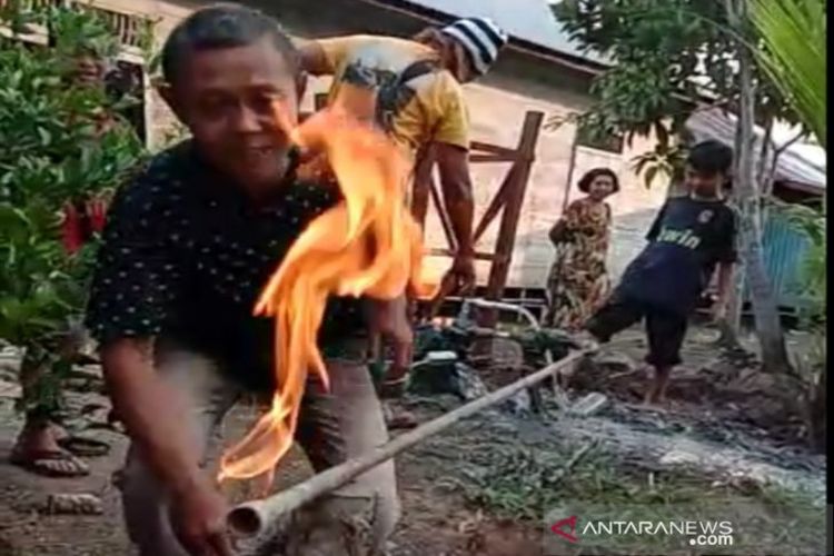 Seorang warga di Kabupaten Barito Kuala, Kalimantan Selatan saat mendekat di sumur bor yang mengeluarkan gas hingga menyala disulut api.