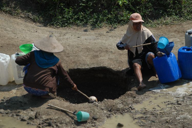 Warga Desa Cekel, Kecamatan Karangrayung, Kabupaten Grobogan, Jawa Tengah mengumpulkan air dari lubang galian di dasar sungai yang mengering, Minggu (3/9/2017). Warga terpaksa harus menggali tanah di alur sungai yang tandus demi mendapatkan air akibat kemarau panjang yang melanda wilayah ini.?