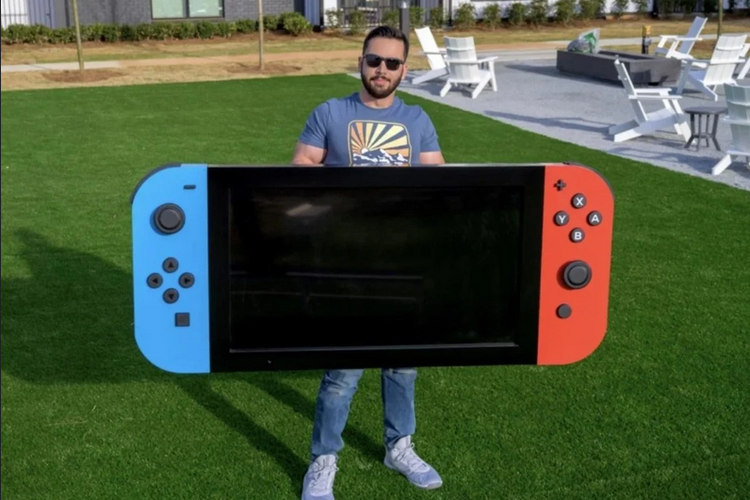 Seorang YouTuber bernama Michael Pick yang sedang memegang Nintendo Switch berukuran raksasa