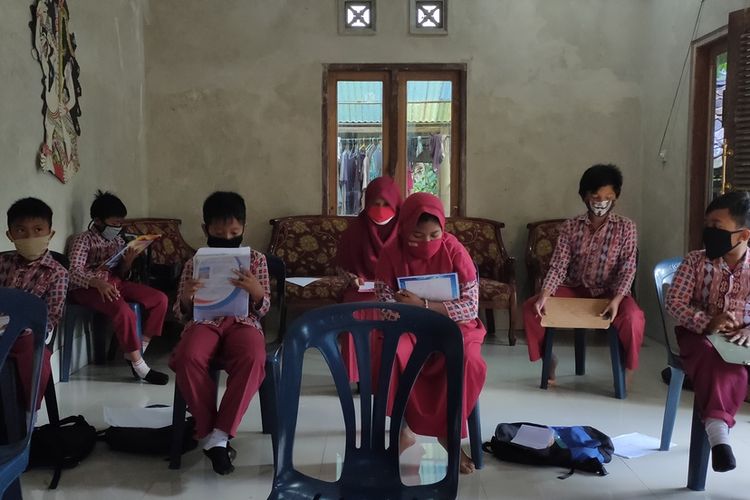 Belasan pelajar mengikuti Penilaian Tengah Semester (PTS) di sebuah rumah pada Pedukuhan Sanggrah Kidul, Purwosari, Girimulya, Kulon Progo, DI Yogyakarta. Warga rela menyediakan ruang tamunya untuk anak-anak duduk saling berjarak satu dengan lain. Mereka bercampur baik kelas 1 hingga kelas 6 dari SD Tegalsari.