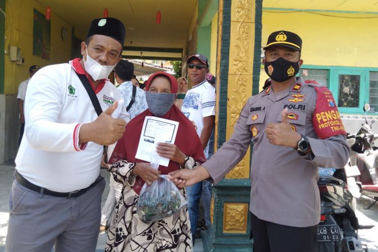 Kepala Desa Randuboto Andhi Sulandra (kiri), saat memberikan kerang hijau sebagai hadiah kepada salah seorang warga yang mengikuti vaksinasi, Rabu (29/9/2021).