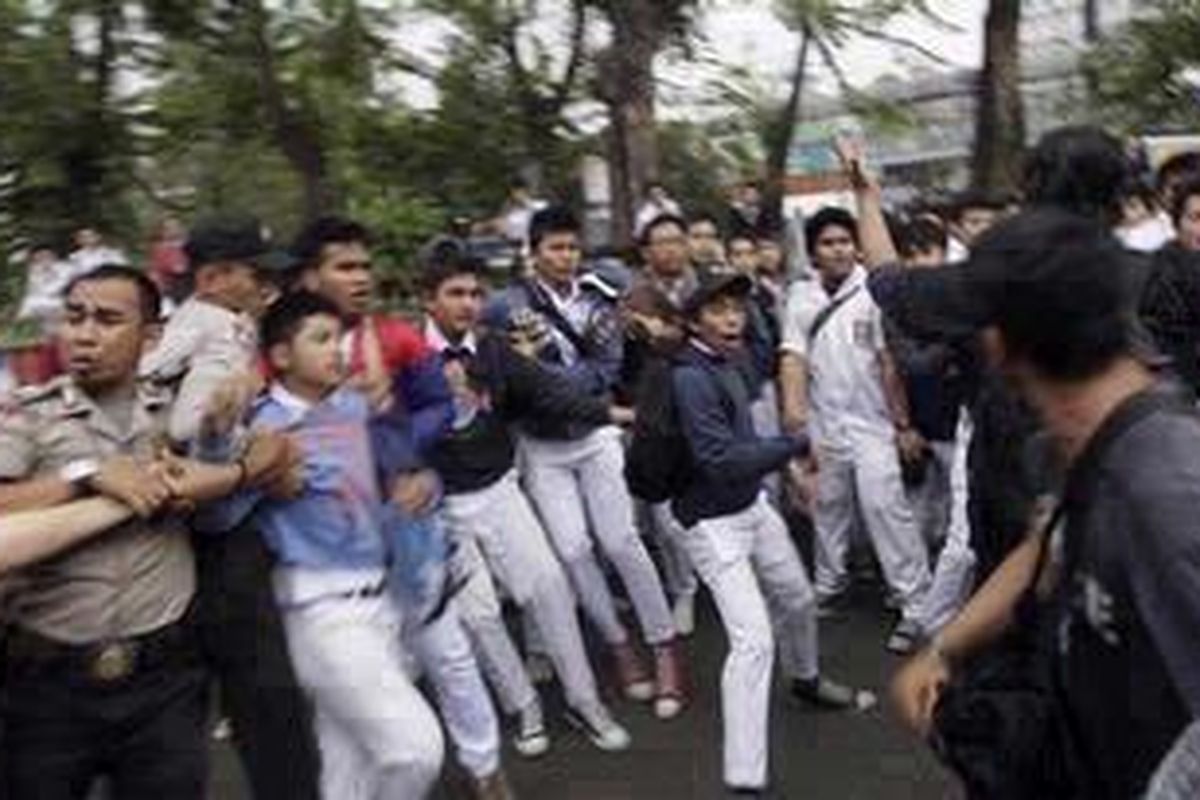 Siswa SMAN 6 dihalangi polisi dan sejumlah guru saat berhadapan dengan sejumlah wartawan di depan SMAN 6, Bulungan, Jakarta Selatan, Senin (19/9/2011). Fotografer Kontan, Fransiskus Simbolon (kanan) mencoba bertahan dari serangan para siswa SMAN 6 di kawasan Bulungan, Jakarta Selatan, Senin (19/9/2011). Kejadian ini bermula saat sejumlah wartawan melakukan aksi protes berkaitan dengan kasus perampasan kamera video salah satu wartawan Trans 7 saat meliput tawuran sekolah tersebut.