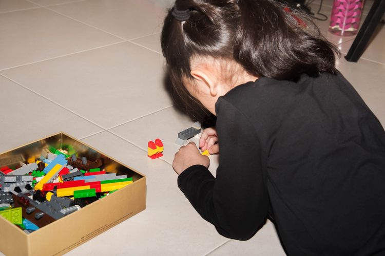 Ilustrasi anak yang sedang bermain lego di atas lantai keramik kamar