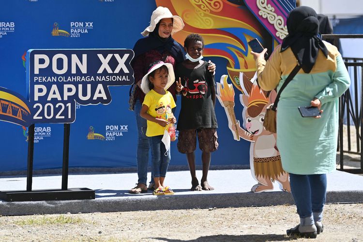 Foto dirilis Jumat (15/10/2021), memperlihatkan warga berfoto dengan latar belakang pernak-pernik PON XX Papua di kawasan Pasar Lama Timika, Kabupaten Mimika, Papua. Presiden Jokowi mengungkapkan, PON XX Papua bukan hanya kompetisi olahraga semata, namun sebagai arena bersama untuk merayakan keragaman, mempertebal persaudaraan serta memperkuat persatuan dan kesatuan.