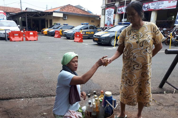 Nanik (54), penjual jamu keliling sedang melayani pelanggan setianya di kawasan Palmerah, Jakarta Barat, Kamis (31/1/2019).