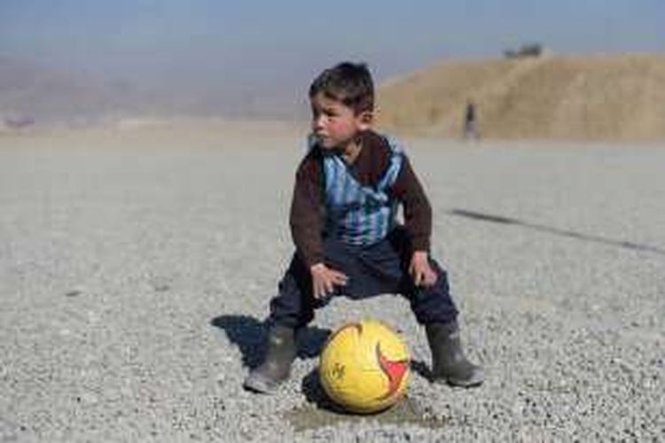 Murtaza Ahmadi (5) memakai kaus sepak bola Argentina yang terbuat dari kantong plastik bertuliskan nama sang idola, Lionel Messi, saat bermain sepak bola di Kabul, Afganistan, 1 Februari 2016.