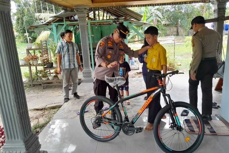 Kapolsek Siak Hulu AKP Zainal Arifin menyerahkan hadiah sepeda kepada Andreas, siswa SMP yang menggagalkan aksi pelaku begal di Kecamatan Siak Hulu, Kabupaten Kampar, Riau, Selasa (14/2/2023).