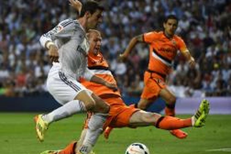 Bek Valencia, Jeremy Mathieu, saat berupaya menghadang laju gelandang Real Madrid, Gareth Bale, dalam lanjutan Primera Divison di Stadion Santiago Bernabeu, Minggu (4/5/2014). 