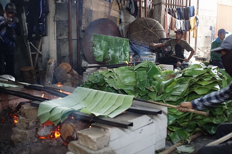 A number of workers burned pieces of banana leaves to wrap basket cakes at the Dodol and Ny Cake production house. Lauw (LKW), in Tangerang, Banten, Friday (17/1/2025). The burning process uses chunks of tree trunks.