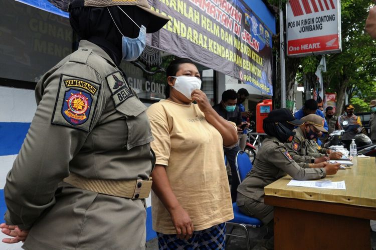 Satu dari puluhan warga yang terjaring razia karena tidak memakasi masker, menerima sanksi sosial di lokasi razia. Pada Kamis (5/11/2020), petugas gabungan menggelar operasi yustisi di Bundaran Ringin Contong, Kabupaten Jombang, Jawa Timur.