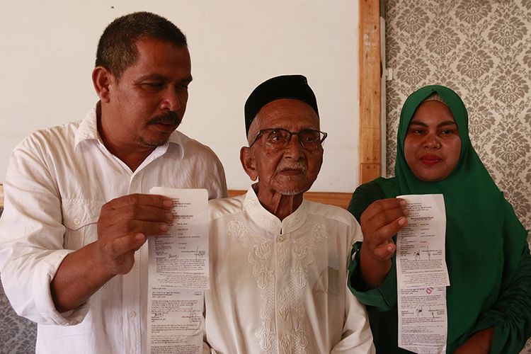 Nyak Sandang (tengah) bersama anaknya Khaidar (kanan) dan Nailis Safwati (menantu) memperlihatkan tiket keberangkatan umrah yang dijadwalkan pada Maret mendatang, Senin (18/2/2019). 