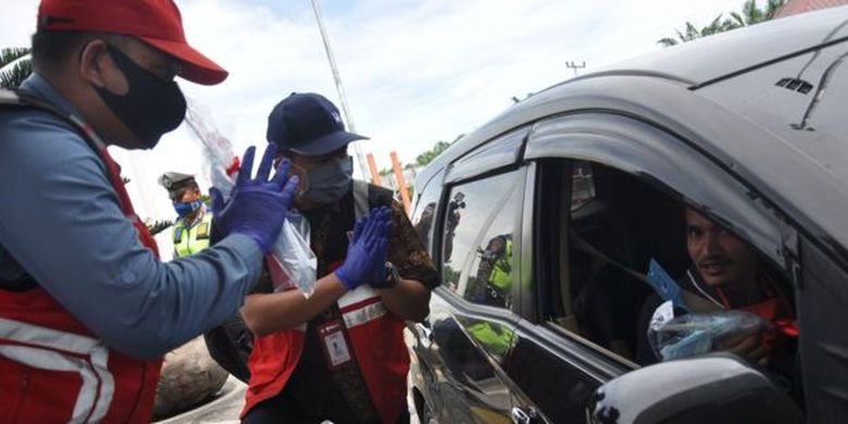 Petugas PT Hutama Karya memberikan ienderamata kepada pengguna tol saat memberikan imbauan agar tidak mudik di ruas gerbang tol Medan-Binjai, Sumatera Utara, Kamis (30/4). Pihak kepolisian bersama operator tol PT Hutama Karya mengimbau kepada masyarakat pengguna jalan tol untuk tidak mudik guna memutus rantai penyebaran Covid-19. 