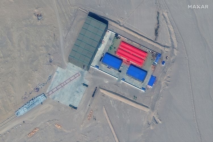 Citra satelit dari Maxar Technologies memperlihatkan rel dan bangunan gudang target di Ruoqiang, China, Kamis (7/10/2021). Pemantauan satelit mengungkap China membangun tiruan kapal perang Amerika Serikat, baik kapal induk maupun kapal perang, untuk target latihan perang.
