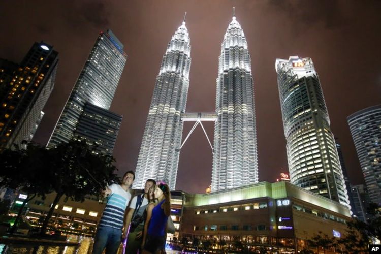 Wisatawan berfoto cinderamata di gedung ikonik Malaysia, Menara Kembar Petronas di Kuala Lumpur, Malaysia, Kamis, 14 Januari 2016.