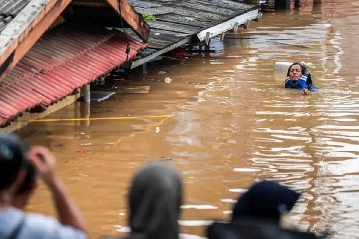 Seorang warga melintasi banjir di Pancoran, Jakarta Selatan pada 4 Maret 2025.