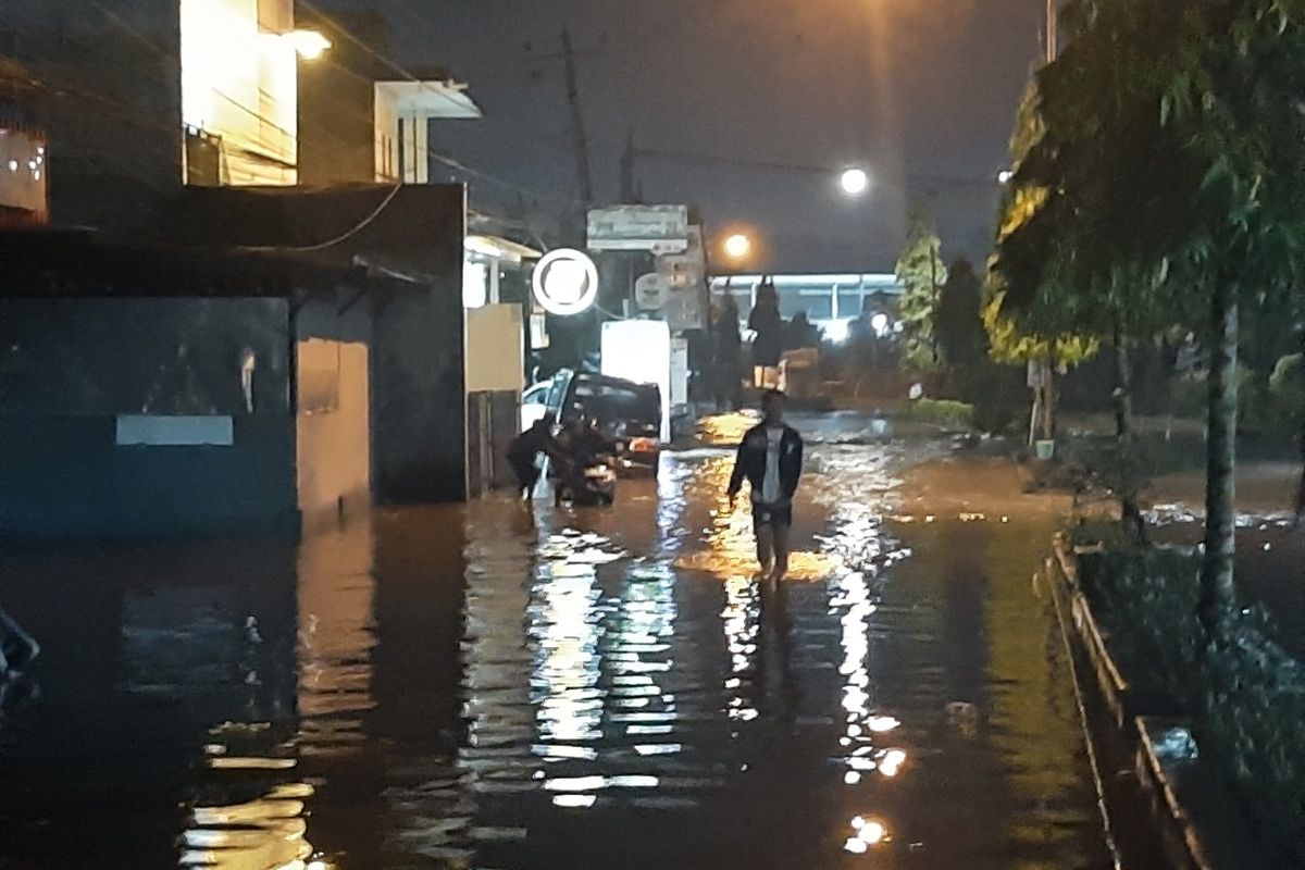 Seorang warga saat berjalan kaki melintasi Jalan Stadion Wedomartani, Kapanewon Ngemplak, Kabupaten Sleman yang terendam air akibat diguyur hujan deras.
