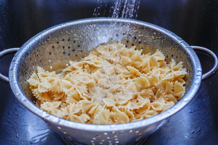 Ilustrasi mencuci pasta dengan air setelah merebusnya.