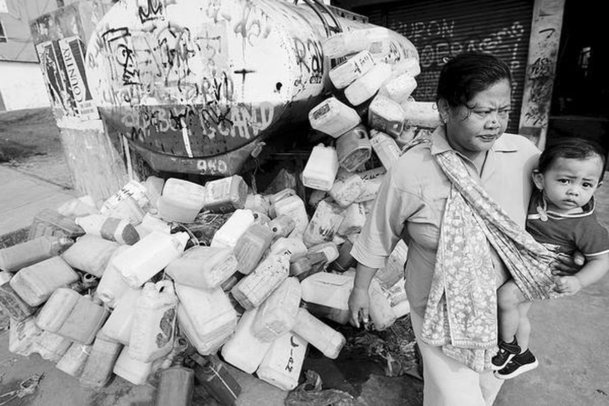Warga melintas di samping puluhan jeriken di salah satu agen minyak tanah di Jalan Raden Saleh, Karang Tengah, Ciledug, Tangerang, Selasa (29/4). Sebagian warga di sekitar wilayah itu tetap mengantre minyak tanah karena belum mendapat pembagian kompor dan tabung gas.  