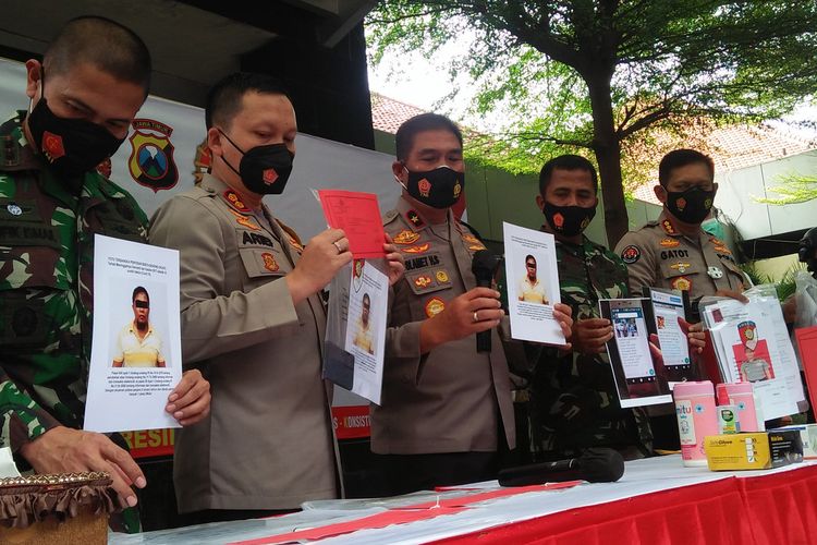 Aparat kepolisian menunjukkan foto pembuat dan penyebar kabar hoaks Kasdim 0817 Gresik meninggal dunia usai divaksin, dalam rilis pengungkapan kasus di halaman Mapolres Gresik, Rabu (20/1/2021).