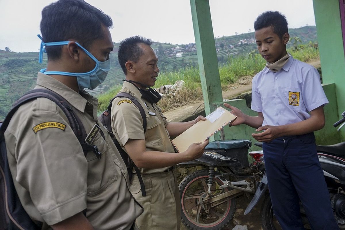 Kepala sekolah SMP N 4 Bawang Mulud Sugito (tengah) bersama guru wiyata menyerahkan lembar tugas soal kepada siswa yang belajar di rumah di Pranten, Bawang, Kabupaten Batang, Jawa Tengah, Selasa (2/6/2020). Sejak diberlakukannya belajar di rumah untuk siswa saat adanya pandemi COVID-19, sejumlah guru dan siswa yang belum menguasai teknologi menerapkan jemput bola oleh guru di rumah siswa dengan mengantar lembar penugasan penilaian akhir tahun dengan berjalan melalui perbukitan yang menempuh jarak sekitar satu kilometer. ANTARA FOTO/Harviyan Perdana Putra/hp.