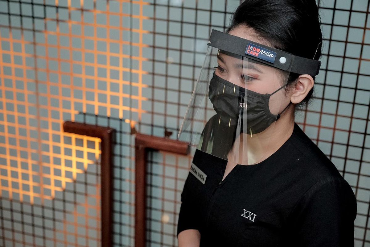 Petugas bioskop mengenakan masker dan face shield