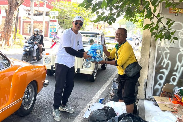 Salah satu anggota Volkswagen Jawa Timur membagikan sembako kepada masyarakat tidak mampu yang ditemui saat konvoi memperingati Hari Kemerdekaan RI ke-80 dan merayakan HUT Volkswagen Indonesia ke-32 di Surabaya, Sabtu (16/8/2025) siang.