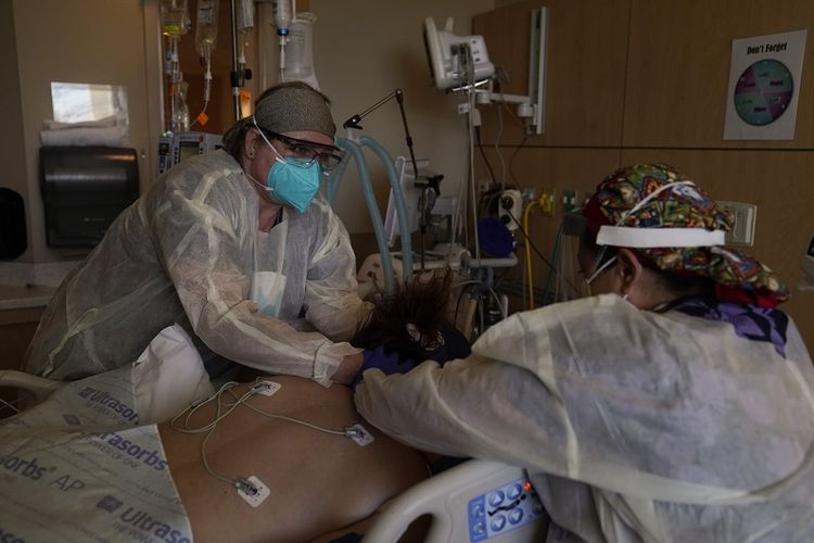 Dalam file foto 22 Desember 2020 ini, perawat Robin Gooding, kiri, dan Johanna Ortiz merawat pasien Covid-19 di Providence Holy Cross Medical Center di bagian Mission Hills di Los Angeles. 
