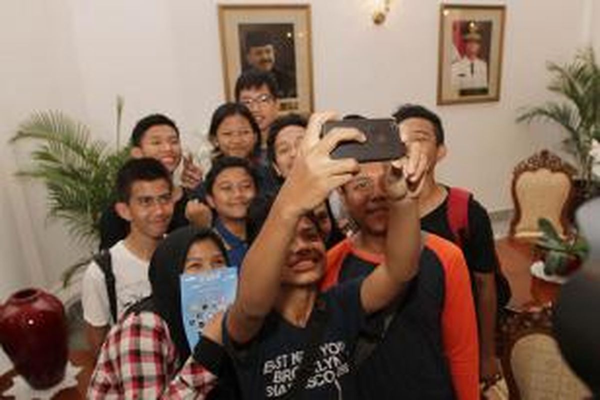 Warga berfoto di Balai Kota DKI Jakarta saat berwisata, Sabtu (12/9/2015).
