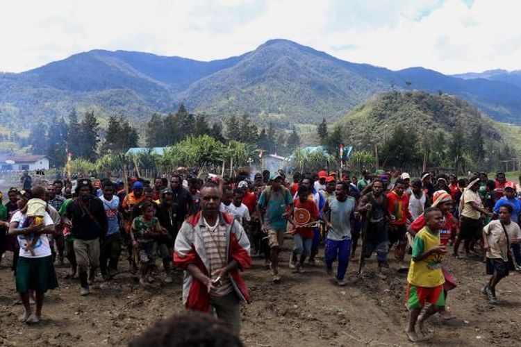 Warga bersama-sama memasuki lapangan Trikora untuk memulai acara adat bakar batu di Lapangan Trikora Distrik Ilaga, Kabupaten Puncak, Papua, Kamis (15/9/2016). Tradisi bakar batu merupakan salah satu tradisi terpenting di Papua yang berfungsi sebagai tanda rasa syukur, menyambut tamu, atau acara perdamaian setelah perang antar suku.