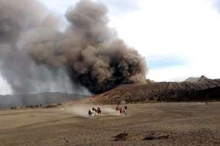 Wisatawan menikmati keelokan Gunung Bromo di Kabupaten Probolinggo, Jawa Timur, dengan latar belakang pemandangan hembusan asap dan abu vulkanik erupsi Gunung Bromo, Selasa (12/7/2016) . Status Gunung Bromo hingga kini waspada, dengan aktivitas vulkanik terus fluktuatif.