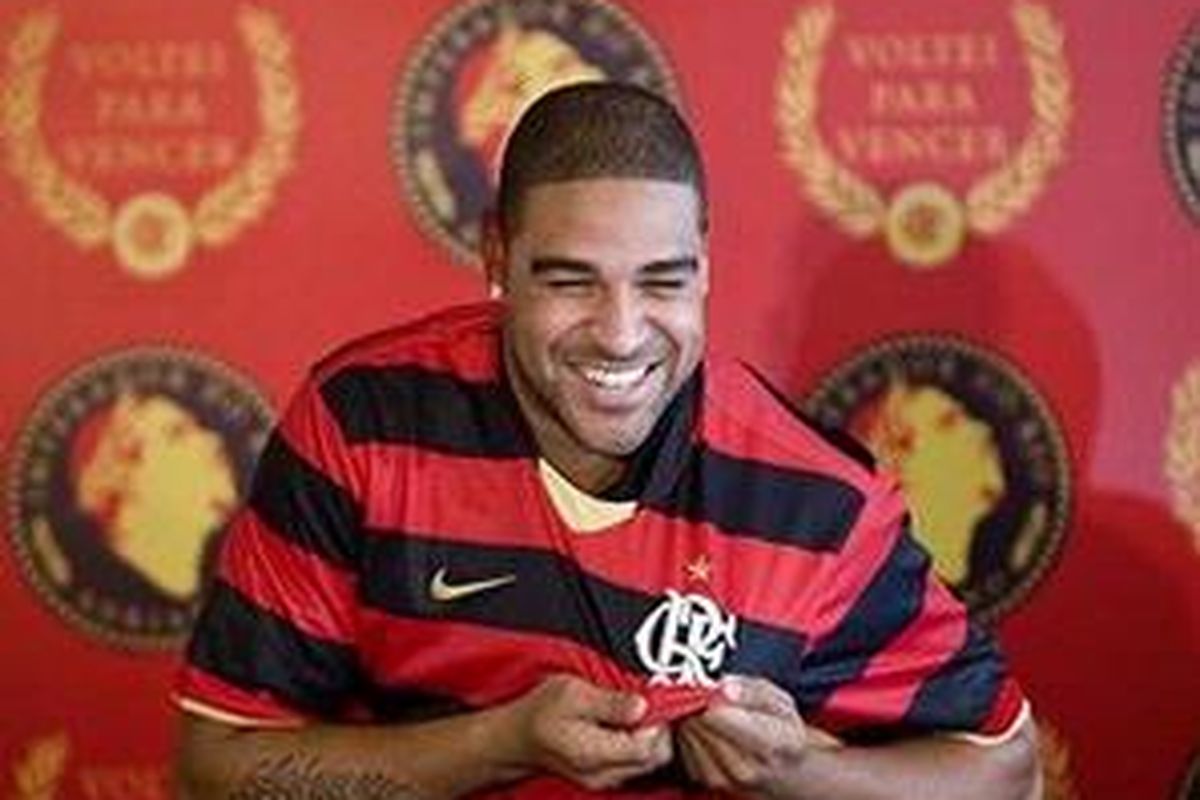 Adriano dengan gembira memperlihatkan kostum Flamengo saat diperkenalkan ke hadapan wartawan.