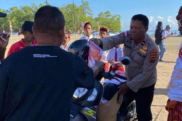 Anggota kepolisian menyerahkan baju merah putih kepada warga, dalam rangka memperingati HUT ke-78 Republik Indonesia di Motaain, Belu, Nusa Tenggara Timur, wilayah perbatasan Indonesia dengan Timor Leste. 
