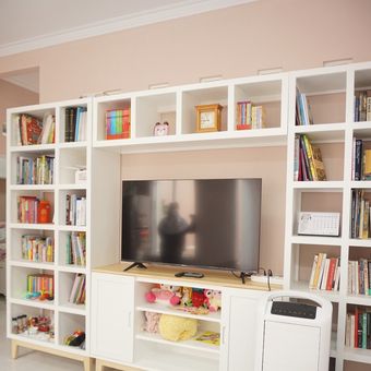 Ilustrasi TV dikelilingi rak buku di ruang tamu. 
