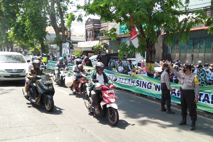 Aparat kepolisian memberi himbauan kepada massa pendukung Paslon dan pengguna jalan untuk mematuhi protokol kesehatan, sebagian mengatur lalu lintas di depan kantor KPU Gresik, Minggu (6/9/2020).